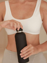 Woman in white sports top holding a black water bottle